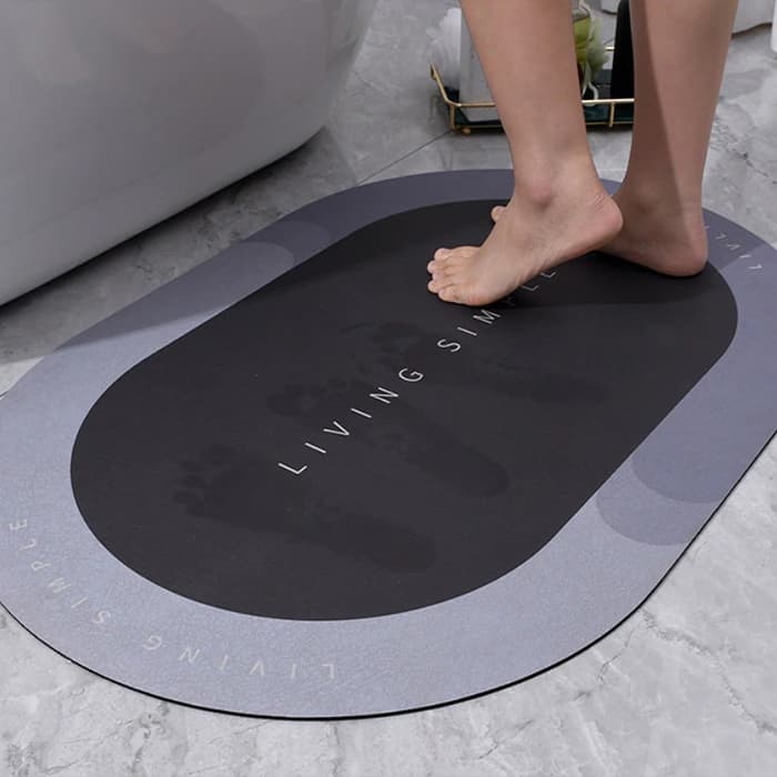 Černá protiskluzová podložka s nápisem "Living Slim" pod bosou nohou na světlé podlaze, určená pravděpodobně do koupelny nebo fitness prostoru.